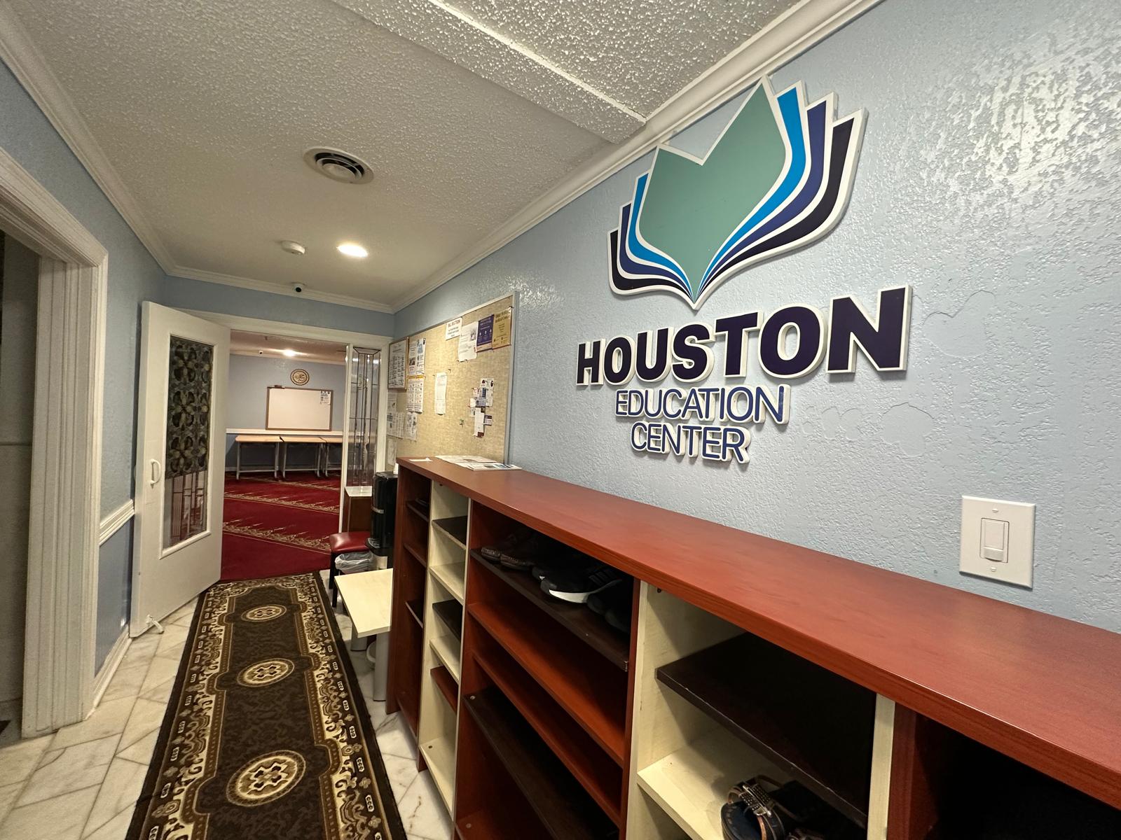 The entrance hallway at Fatih Masjid, with shoe shelves and the Houston Education Center sign
