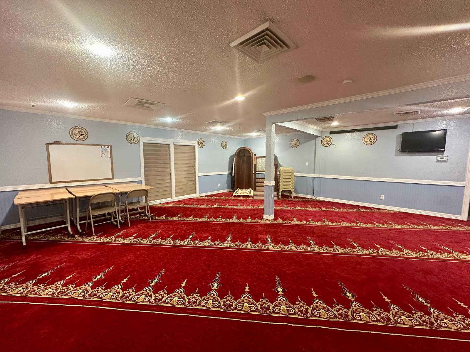 The main prayer hall at Fatih Masjid, with its red patterned carpet and wooden mihrab